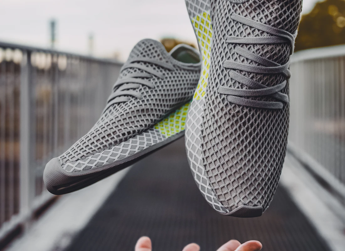 Grey knit sneakers floating above an open hand