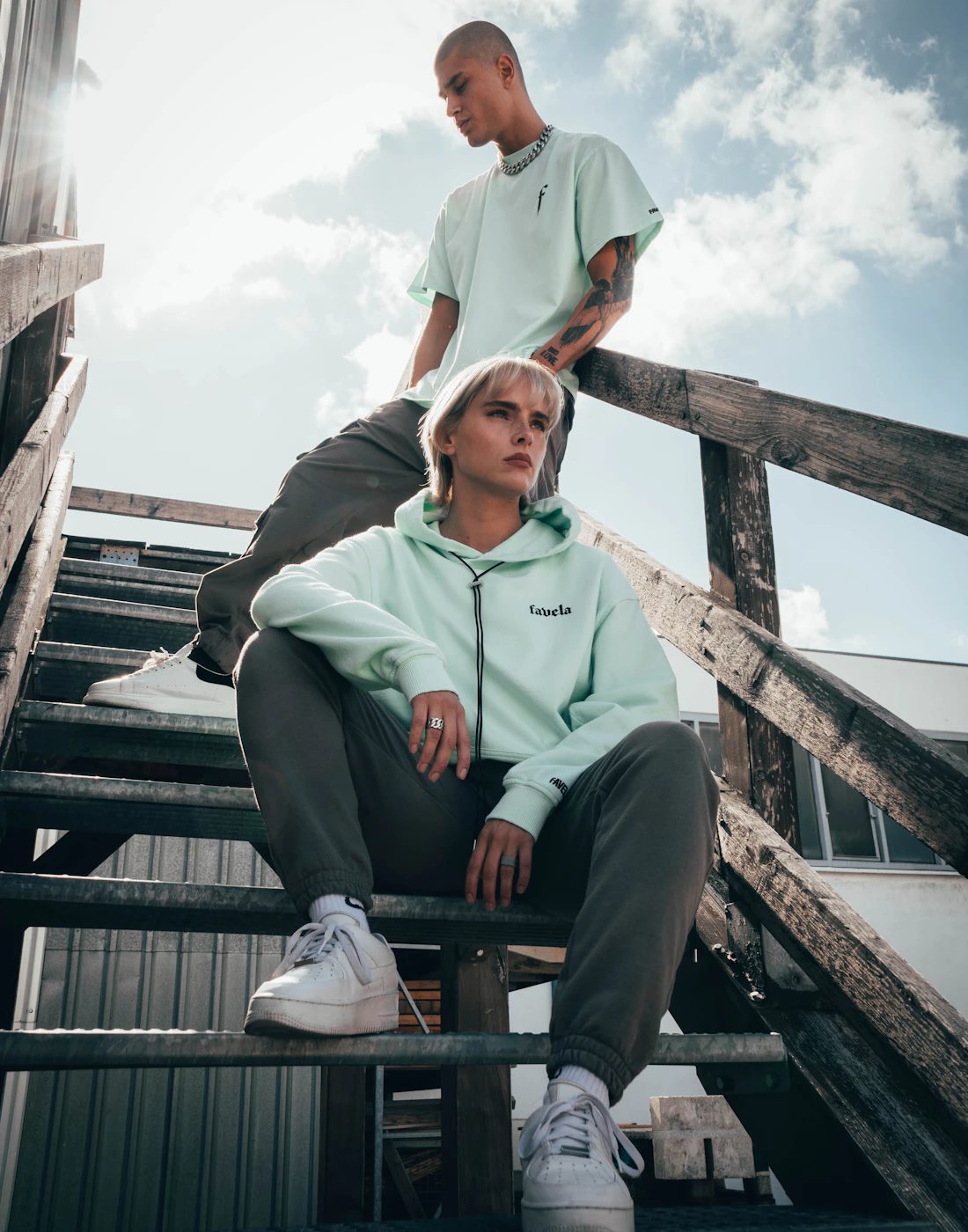 Two young men in hoodies and tees sitting on outdoor stairs