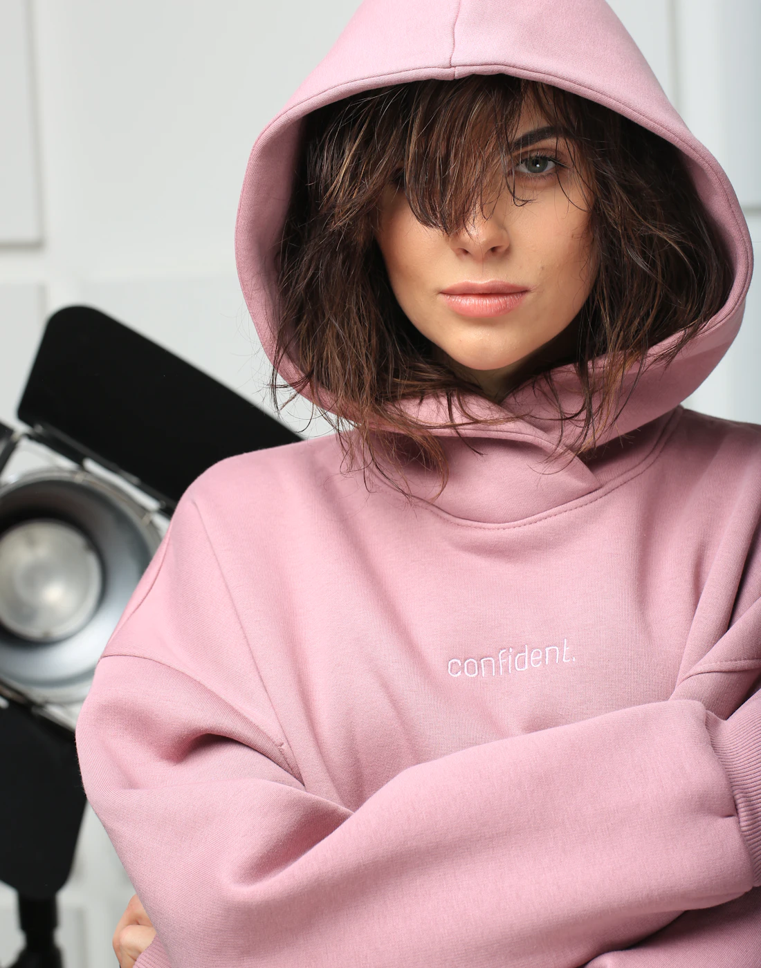 Woman wearing an oversized pink hoodie with the hood up