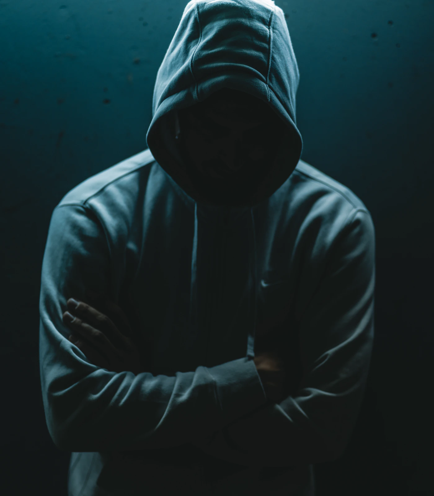 Figure in a dark hoodie with the hood up, in low light