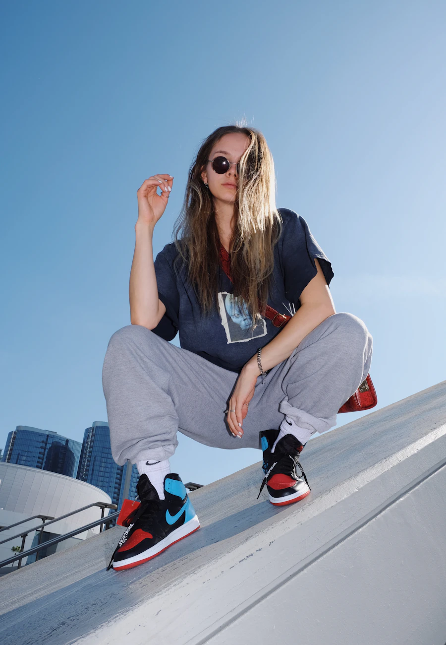Woman in an oversized tee, cargos and high-top sneakers crouching on a rooftop