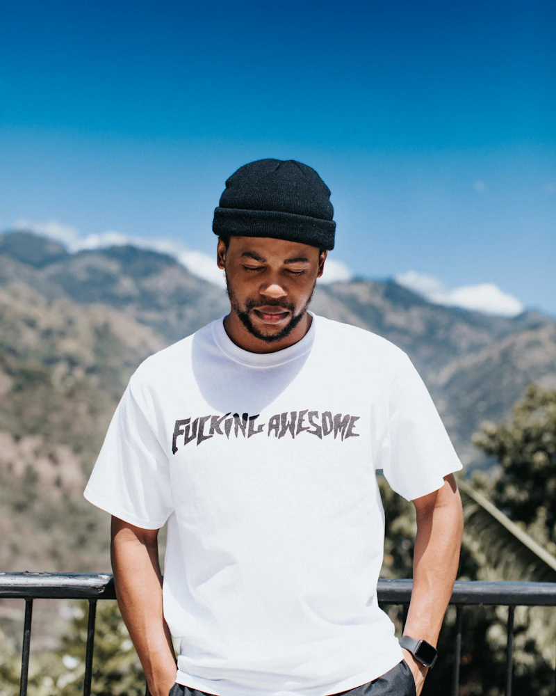 Man in a white graphic tee and beanie in the hills