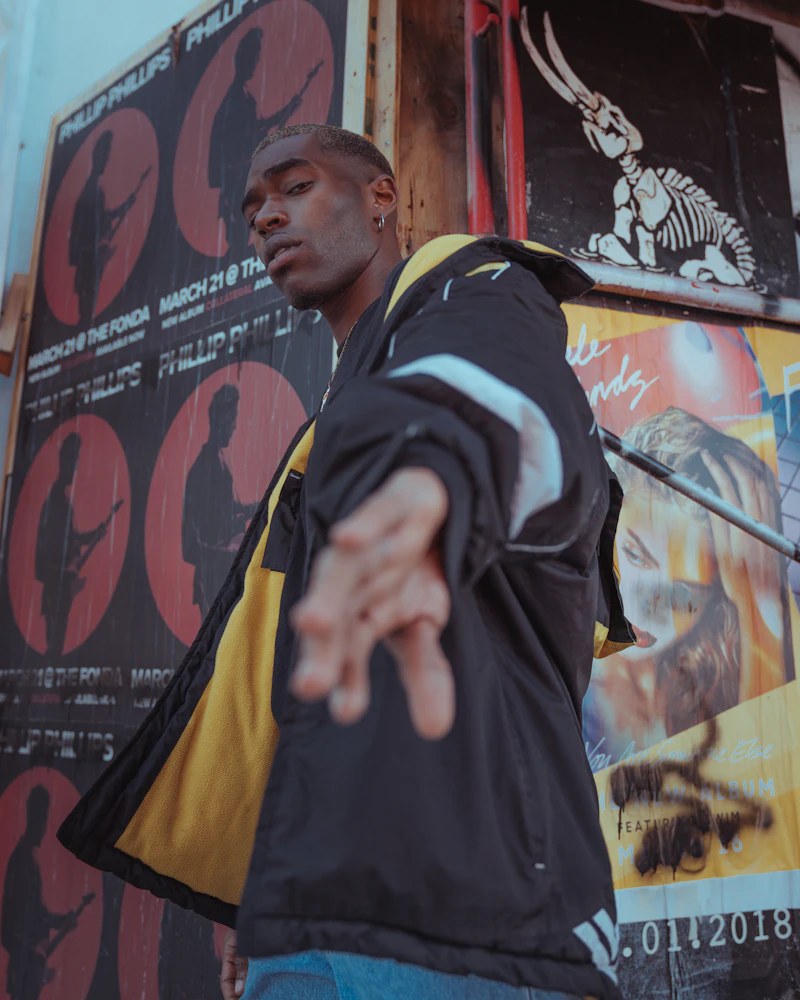 Man in a varsity jacket in front of a graffiti wall