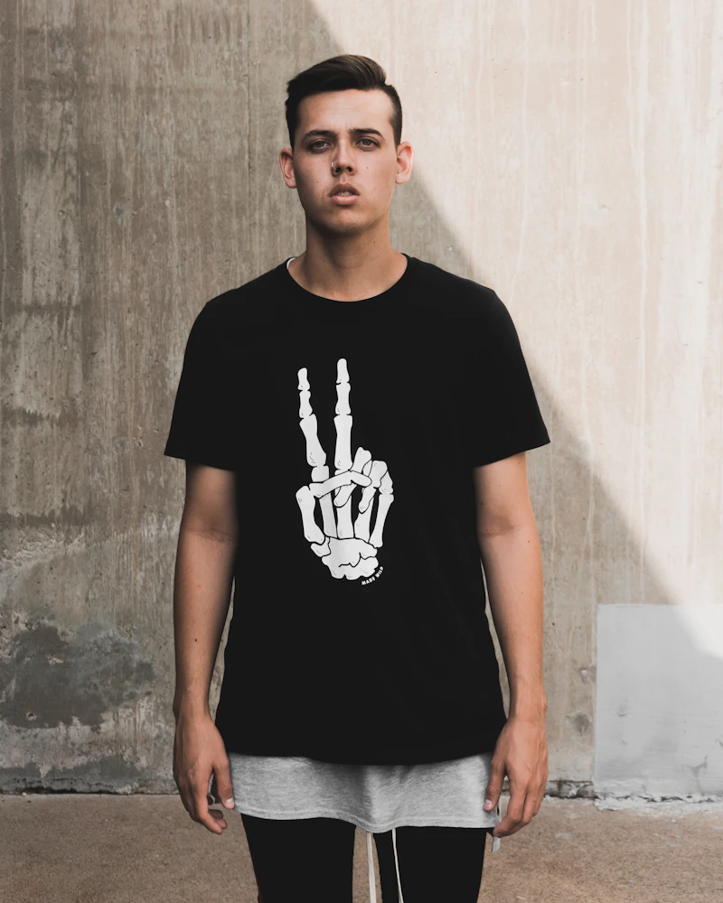 Man in a black graphic tee against a concrete wall